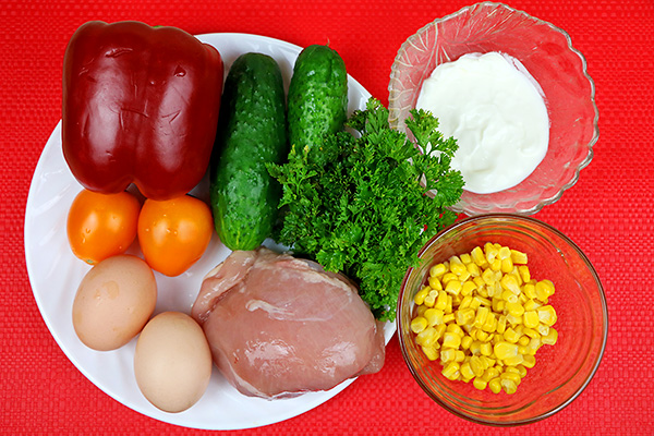 Барвистий салат з курячого філе, червоного перцю, огірків, яєць, помідорів та кукурудзи